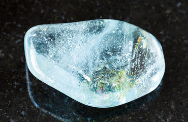 closeup of sample of natural mineral from geological collection - polished blue Topaz rock on black...