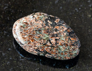closeup of sample of natural mineral from geological collection - tumbled Titanite (Sphene) rock on...