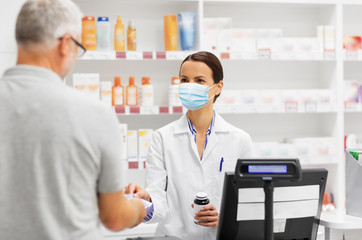 medicine, pharmaceutics, health care and people concept - apothecary wearing face protective...