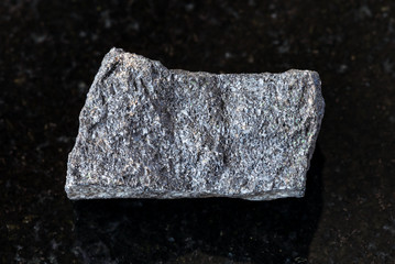closeup of sample of natural mineral from geological collection - unpolished Chromite rock on black...