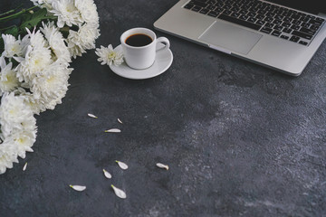 there is a coffee mug and a laptop on the table, white chrysanthemum flowers are poison
