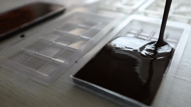 Liquid homemade chocolate is poured into molds.
