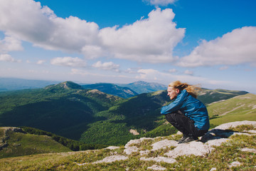 A guy with long hair is sitting on top of a mountain.