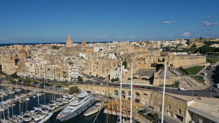 Fototapeta na wymiar Aerial view of sailboats moored in harbour Senglea and Birgu, Bormla / Cospicua, Valletta, Malta. Ancient architecture of old town: christian orthodox churches, cathedrals, basilicas. Sunny day, blue 