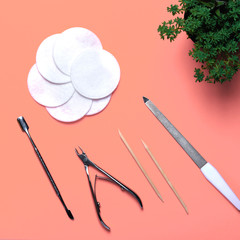 Top view of equipment for manicure and pedicure on a pink background. Tongs, nail file, pusher,...