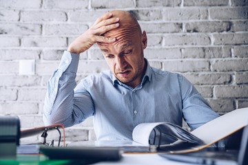 Finacial problems and crisis. Stressed depressed man reading bills and loan contract. Finacial problems and crisis