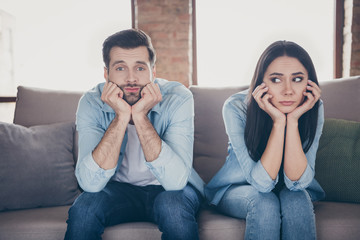 Portrait of stressed frustrated couple man woman sit divan have nothing to do on covid-19 quarantine feel bored wear denim jeans shirt in house indoors
