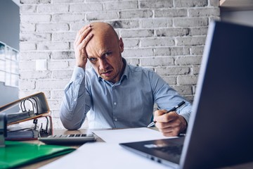 Finacial problems and crisis. Stressed depressed man reading bills and loan contract. Finacial...