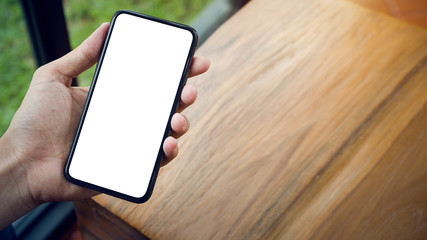 hand holding a smartphone on wooden table.