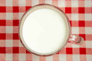 fresh milk in a mug on a red and white tablecloth
