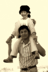 Light sepia picture of a man giving his daughter a piggy back ride