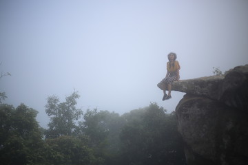 Woman sitting at the edge of a cliff Pa Hin Ngam National Park in Chaiyaphum, Thailand.