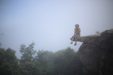Woman sitting at the edge of a cliff Pa Hin Ngam National Park in Chaiyaphum, Thailand.