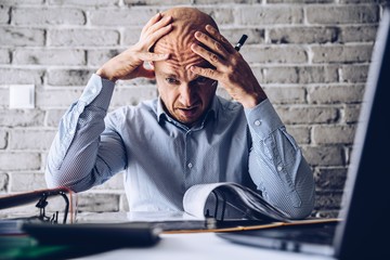 Finacial problems and crisis. Stressed depressed man reading bills and loan contract. Finacial...