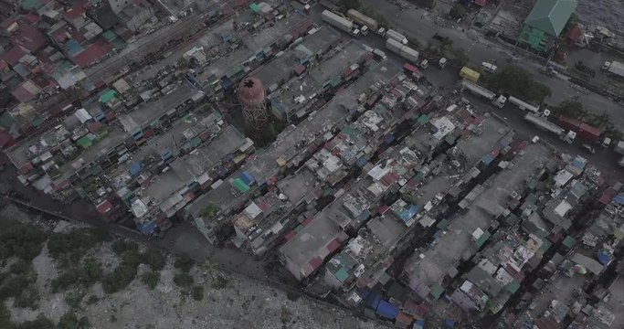 Ungraded, Descending aerial flight over poor housing tilting up revealing harbour. Drone, 4K. 