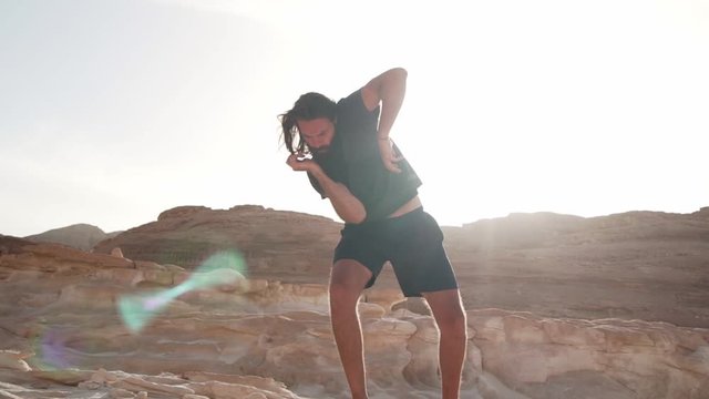 Bearded man dance ecstatic dance in desert in sunshine rapid slow motion