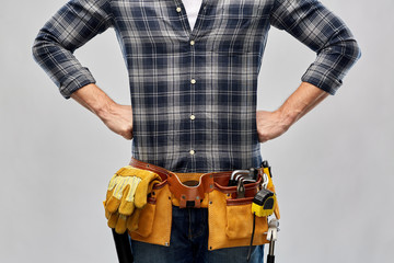 repair, construction and building - male worker or builder with working tools on belt over grey background