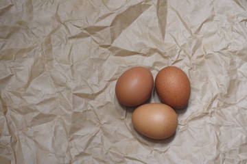 Three chicken brown eggs on the craft paper background.