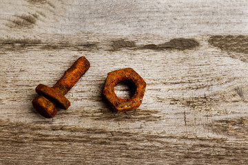 Heavy rusted bolts with washer and nut on the rough and aged wooded surface.