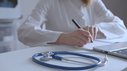 Close up of stethoscope at desk and female doctor