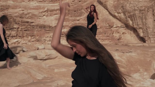 Women in black clothing practice ecstatic dance in canyon