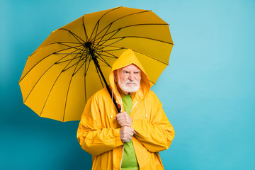 Portrait of his he nice evil outraged irritated annoyed grey-haired man wearing plastic topcoat dislike bad weather isolated over bright vivid shine vibrant blue color background