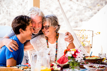 Cheerful caucasian family together with happines - concept of grandfathers and grandson mixed age generations from teenager to senior people with food on table