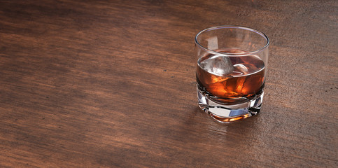 Glass of scotch whiskey and ice. Whisky, bourbon, brandy  or rum on wooden  restaurant table. Glass...