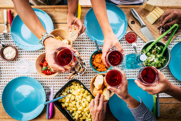Above view of group of friends people eat and drink together celebrating and having fun toasting...