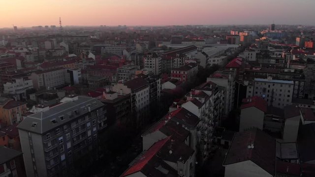 Drone aerial view of Milan skyline from above against sunset over the city. Shot in Lambrate area during Coronavirus lockdown quarantine. Movement is panning onehundredeighty degrees.