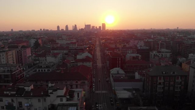 Drone aerial view of Milan skyline from above against colourful sunset over the city. Shot in Lambrate area during Coronavirus lockdown quarantine. Movement is sliding left.