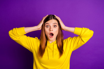 Photo of attractive shocked crazy lady look speechless arms on head open mouth listen awful news wear casual bright yellow hoodie sweatshirt isolated violet color background