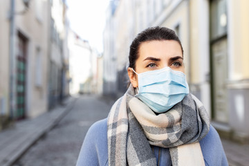 health, safety and pandemic concept - young woman wearing protective medical mask in city
