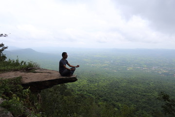 Fototapeta na wymiar Man sitting at the edge of a cliff Sai Thong National Park in Chaiyaphum, Thailand.