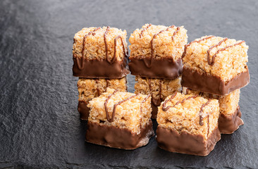 Mini rice and syrup flapjack slices on black stone background