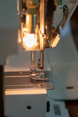 Close up view of sewing machine foot, no material. Overhead light shining down. 