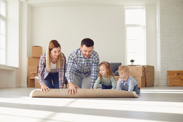 Fototapeta premium Happy family with carpet on the floor in a new apartment.
