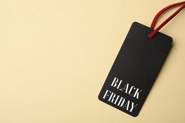 Tag with phrase BLACK FRIDAY on beige background, top view. Space for text