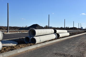 Concrete drainage pipes at the construction site. Laying of underground storm sewer pipes. Installation of water main, sanitary sewer. Installation of concrete sewer wells in the ground