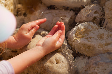 Close-up hand releasing dropping sand. Sand flowing through the hands against blue ocean.