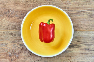 red pod of sweet bell pepper on a green plate on a wooden tabletop