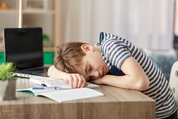 children, education and learning concept - tired student boy sleeping on desk at home