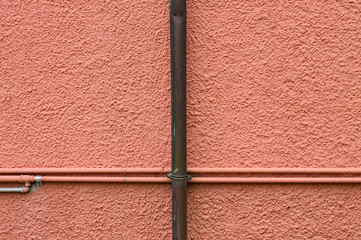 Pink wall with clamped little pipes (Pesaro, Italy, Europe)