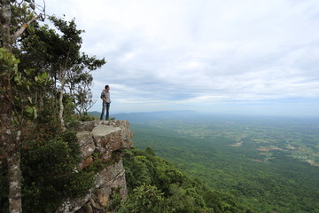 Man standing on a cliff at Mor Hin Khao National Park in Chaiyaphum, Thailand