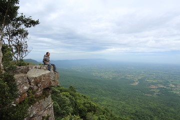 Man sitting on a cliff at Mor Hin Khao National Park in Chaiyaphum, Thailand