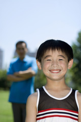 Boy smiling with his father standing in the background
