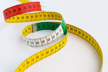 Creative photo of a colorful measuring tape isolated on a white background. Diet and measure concept.