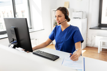 medicine, technology and healthcare concept - happy smiling female doctor or nurse with headset and computer working at hospital