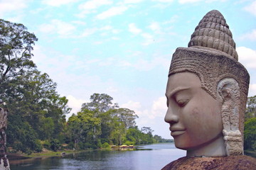 Stone statue Deva at the south gate of Angkor Thom, Angkor Wat. Overlooking the Moat