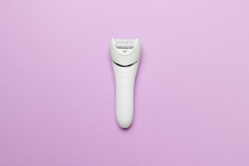 women epilator on purple colored paper background, top view